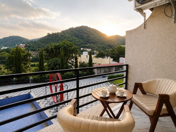 A balcony with a checkered floor, a table with cups and a teapot, and a sofa. - Awecan Radhe Radhe Resort (Qila Kumbhalgarh)
