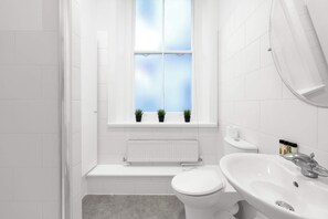 Ein kleines, modernes Badezimmer mit Toilette, Waschbecken und Fenster.