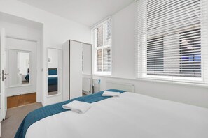 Ein modernes Schlafzimmer mit einem großen Bett, einem Kleiderschrank und einem Spiegel.