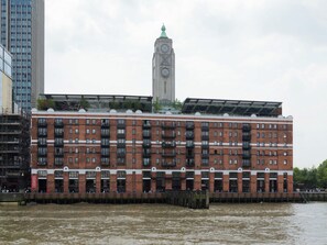 A multi-story building with a clock tower, a river in front, and a bridge with people. - 6SH  one bed in Holborn sleeps 2 (London)