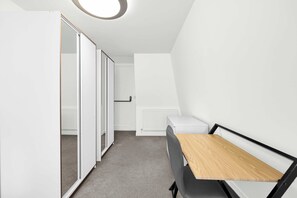 A compact room with a desk, a radiator, and a wardrobe. - 6SH  one bed in Holborn sleeps 2 (London)