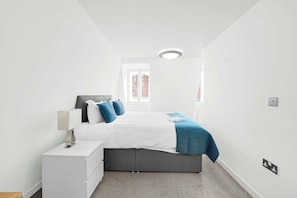Ein Schlafzimmer mit einem Bett, einem Nachttisch und einem Fenster mit Jalousien.