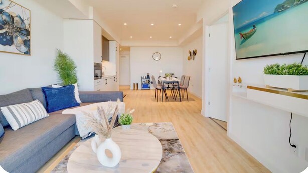 A modern living room with a sofa, coffee table, and a TV mounted on the wall. - Modern Penthouse in Central KW (Kitchener)