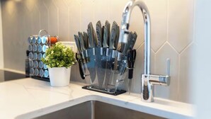 A kitchen counter with a knife block, a potted plant, and a faucet. - Modern Penthouse in Central KW (Kitchener)