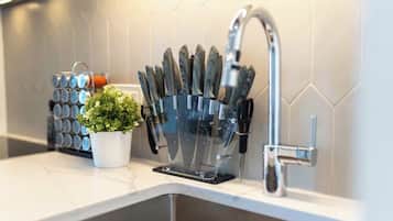 A kitchen counter with a knife block, a potted plant, and a faucet.