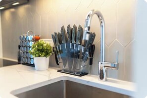 Eine Küchenarbeitsplatte mit einem Messerblock, einem Blumentopf und einem Wasserhahn.