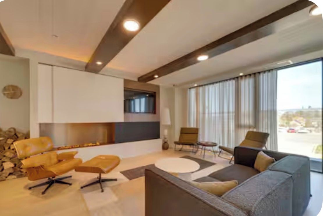 A modern living room with a fireplace, seating area, and large windows.