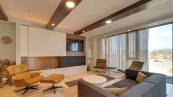 A modern living room with a fireplace, seating area, and large windows.