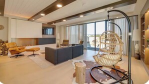 A modern living room with a sofa, chairs, a hanging chair, a fireplace, and a large window. - Modern Penthouse in Central KW (Kitchener)