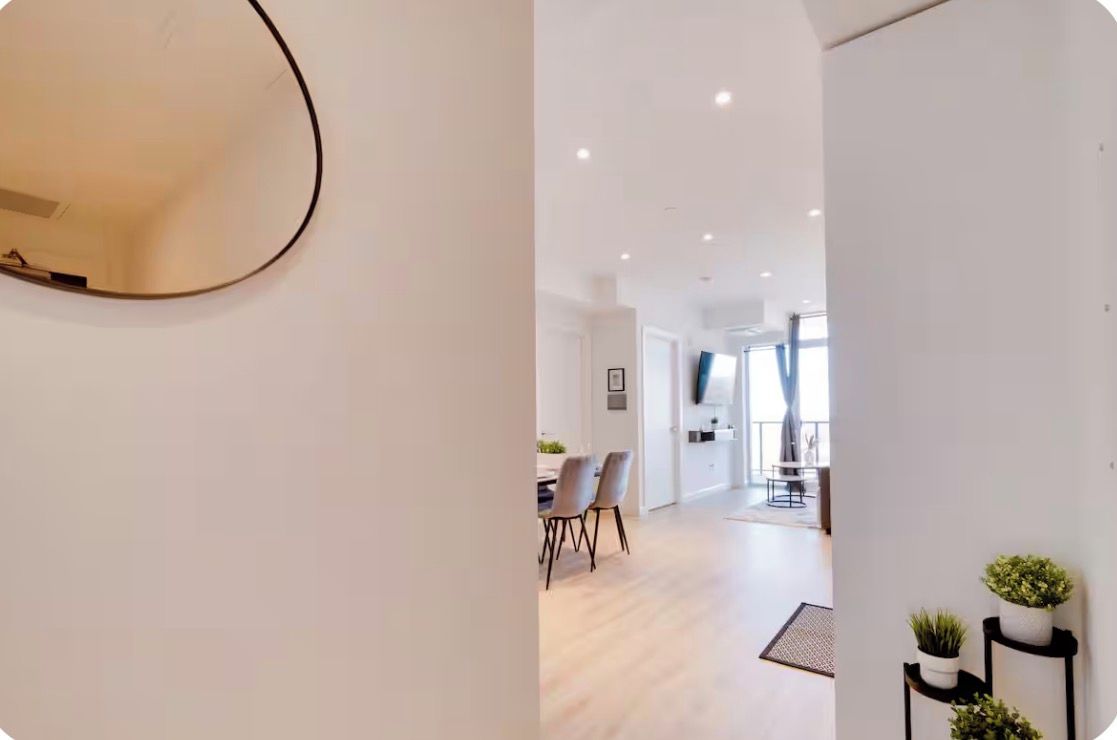 A modern interior with a dining area, a mirror, and a hallway leading to a balcony.