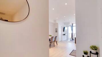 A modern interior with a dining area, a mirror, and a hallway leading to a balcony.