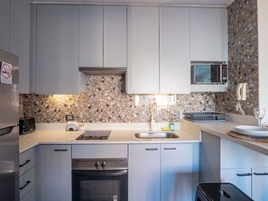A modern kitchen with a granite backsplash, stainless steel appliances, and a microwave. - Costa Home - MUT Costanera & WIFI & Moderno (Santiago)