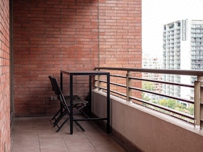 Een balkon met een metalen hekwerk, een tafeltje en een stoel.