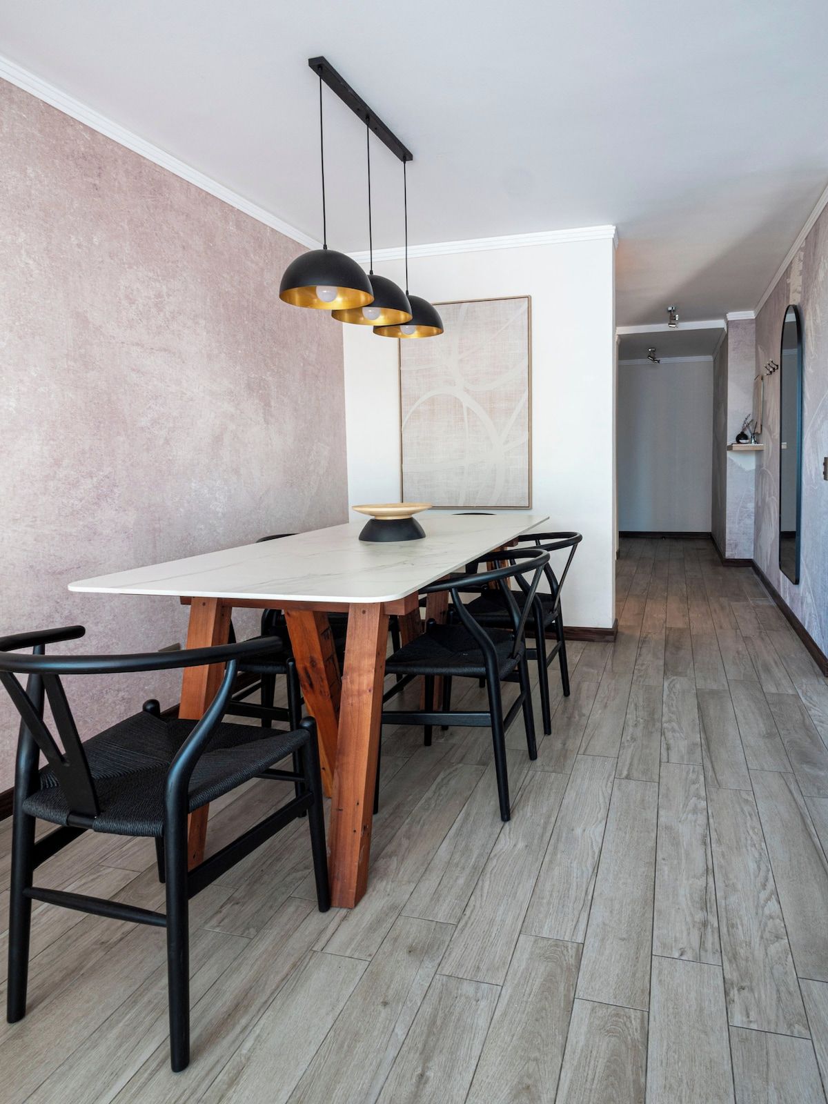 Un comedor con una mesa rectangular, sillas negras y una lámpara colgante.