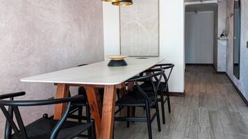Un comedor con una mesa rectangular, sillas negras y una lámpara colgante.