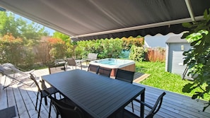 Eine Außenpatio mit Whirlpool, Holzterrasse und Sitzbereich.