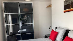 A bedroom with a bed, a nightstand, a lamp, and a sliding door. - Holiday Home 'Villa L'escale 600 M De La Plage' with Private Terrace and Private Garden (Andernos-les-Bains)