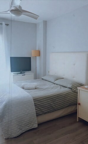A bedroom with a bed, a television, a lamp, and a ceiling fan. - Apartment 'Modern  Cozy Just 5 Mins From' with Shared Pool, Wi-Fi and Air Conditioning (Marbella)