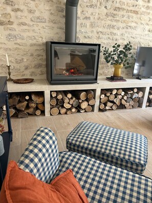A cozy living room with a fireplace, a television, and a stack of firewood. - Charming 2-bedroom house with AC in center of Chablis (Chablis)