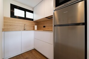 Een moderne keuken met witte kastjes, een roestvrijstalen koelkast en een houten aanrecht.