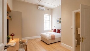 A bedroom with a bed, a desk, and a chair. - Spacious 4-bedroom apartment in peaceful Cape Town with AC (Cape Town)