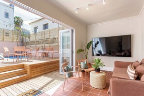 Ein modernes Wohnzimmer mit Fernseher, bequemen Sitzmöglichkeiten, einem Pool und einer Treppe, die in einen Außenbereich führt.