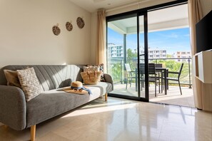 Een moderne woonkamer met een grijze bank, een geweven mand en een hoed op de bank.