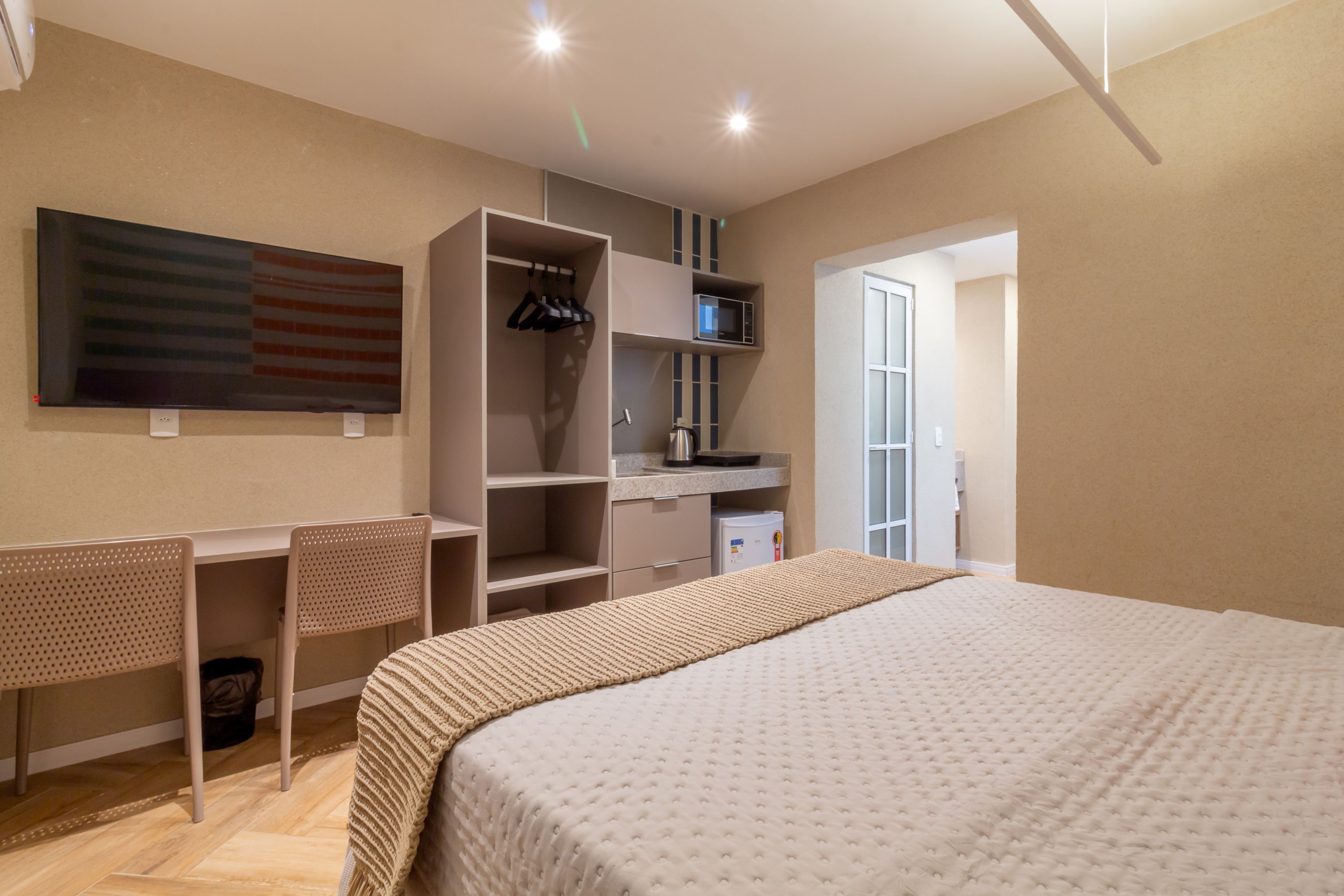 Un dormitorio moderno con una cama grande, un escritorio y un armario.