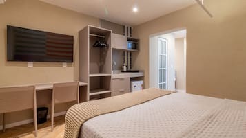 Un dormitorio moderno con una cama grande, un escritorio y un armario.