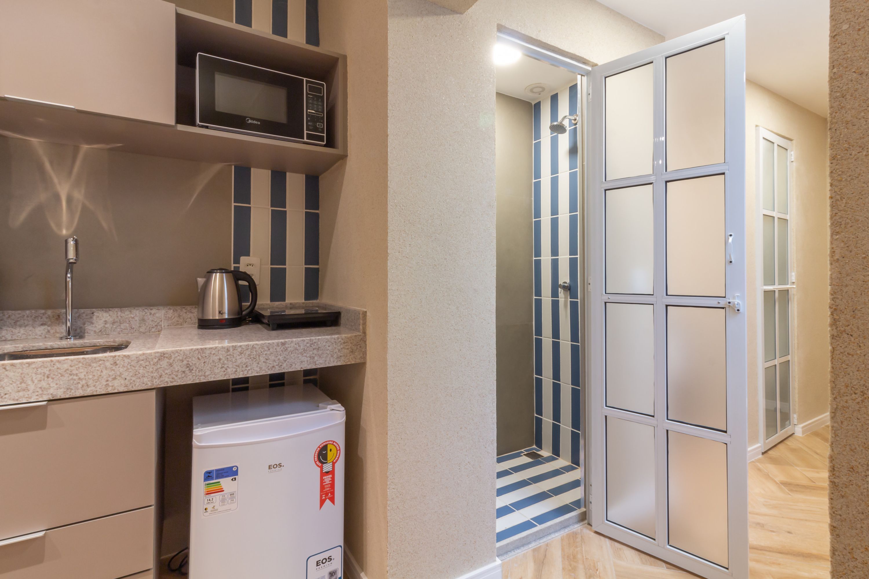 Eine kleine Küchenzeile mit Mikrowelle, Wasserkocher und Kühlschrank.