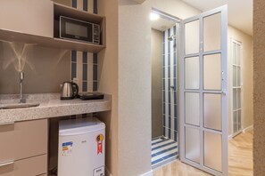 Una kitchenette compacta con microondas, hervidor y refrigerador.