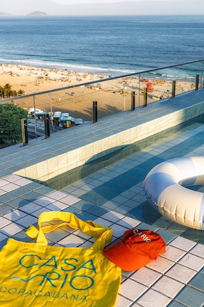 Ein Poolbereich mit Blick auf den Strand, eine gelbe Tasche und eine rote Kappe.