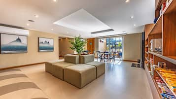 Una sala de estar moderna con un sofá seccional, un comedor con mesa y sillas, y una estantería con aperitivos.