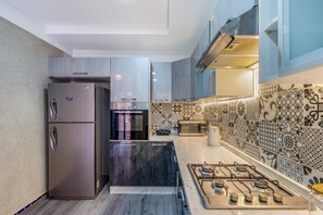 A modern kitchen with stainless steel appliances, a gas stove, and patterned backsplash tiles. - Dar Azur (Swimming Pool & Moroccan Charm) (marakech)