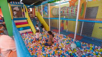 Espaço de recreação infantil com piscina de bolinhas e escorrega.