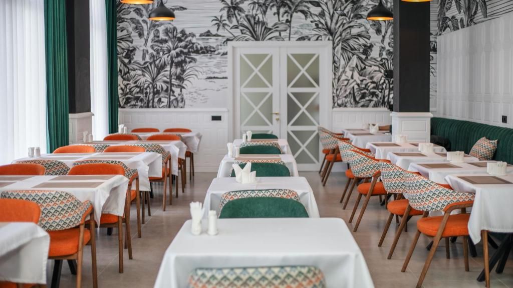 A dining area with tables and chairs, a patterned wall, and a door in the background.