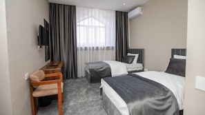 Una habitación de hotel con cama, escritorio, silla y televisor.
