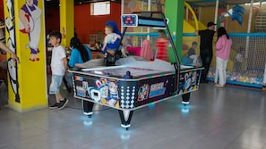 Un área de juegos interior con una máquina de hockey espacial.