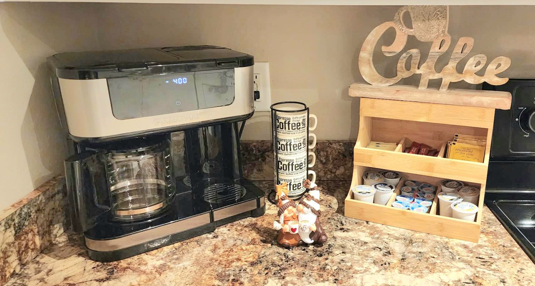 Eine Kaffeemaschine, eine Kaffeetasse und ein Holzregal mit Kaffeethemen und Aufbewahrungsbehältern.