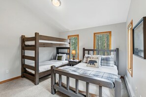 Una camera da letto con un letto a castello, un letto singolo e un comodino con una lampada.