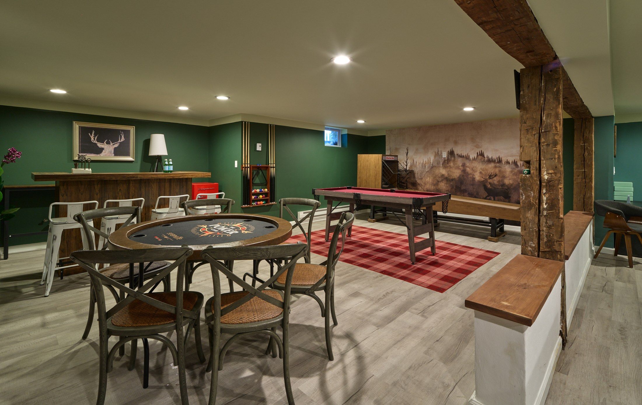 A room with a pool table, chairs, a bar area, and a large wall mural.