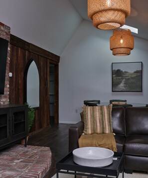 A modern living room with a dark brown leather sofa, a round coffee table, and a large mirror.