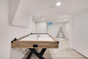 A pool table in a hallway with a modern design, a door, and a Christmas tree in the background.