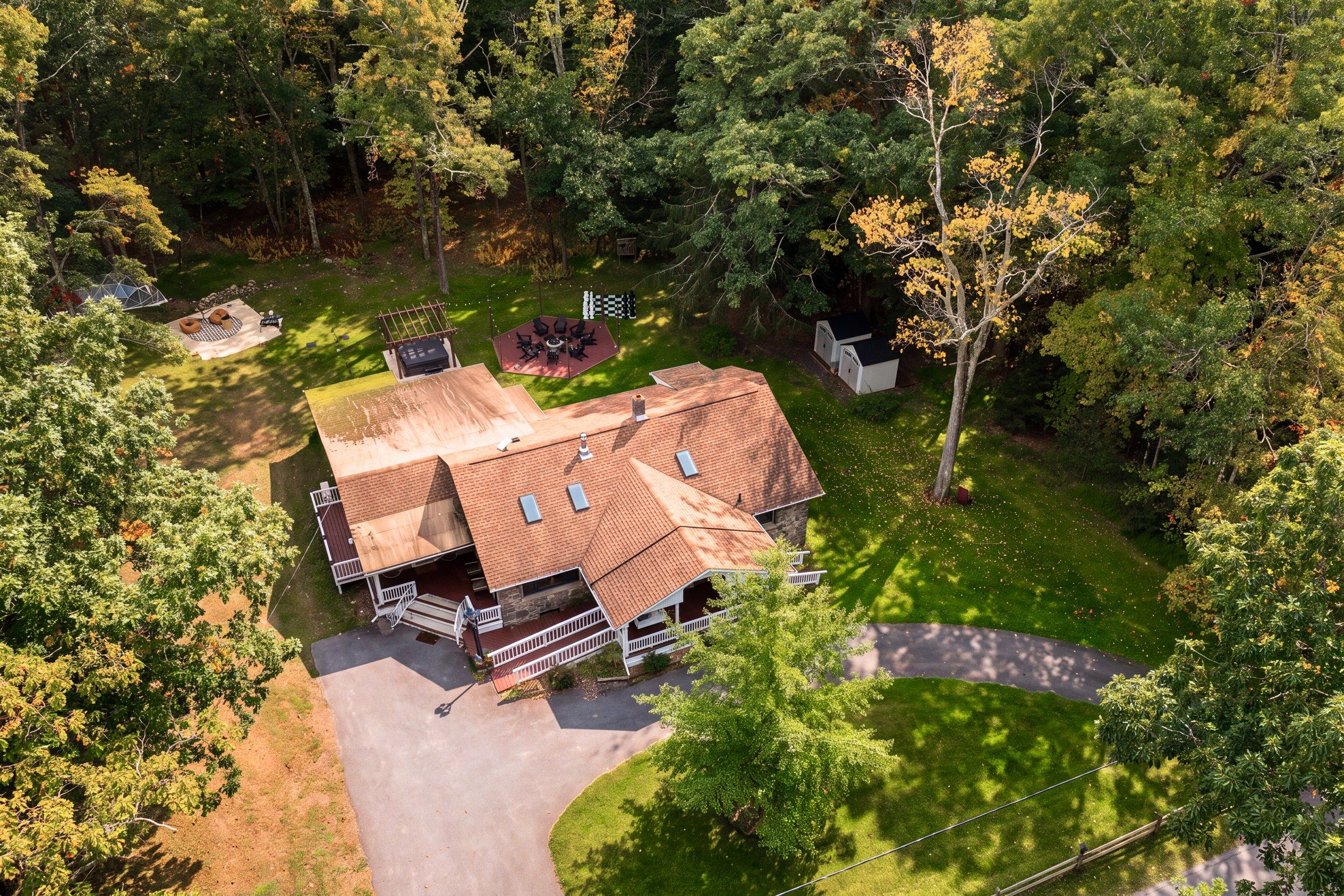 A two-story house with a covered porch, a fenced yard, and a paved driveway.