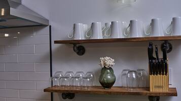 A kitchen counter with a bowl of green apples, a book, and various kitchenware on shelves.