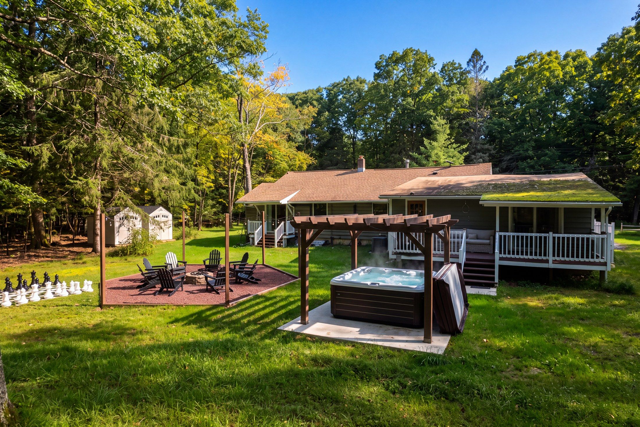 A cozy outdoor area with a hot tub, a chessboard, and Adirondack chairs.