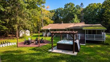 A cozy outdoor area with a hot tub, a chessboard, and Adirondack chairs.
