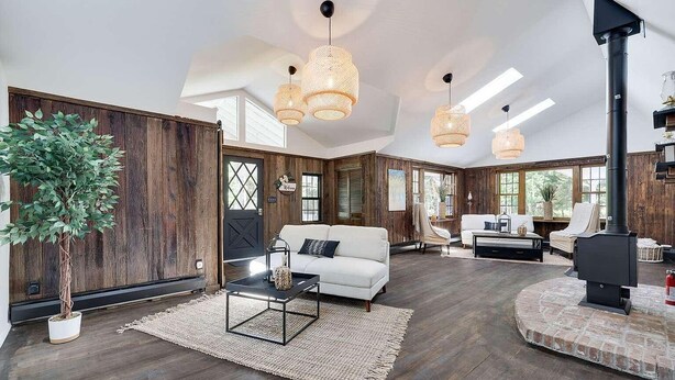 A spacious living area with a white sofa, a coffee table, and a fireplace. - Premium Restored Cabin | Pocono Mountains (Barrett Township)
