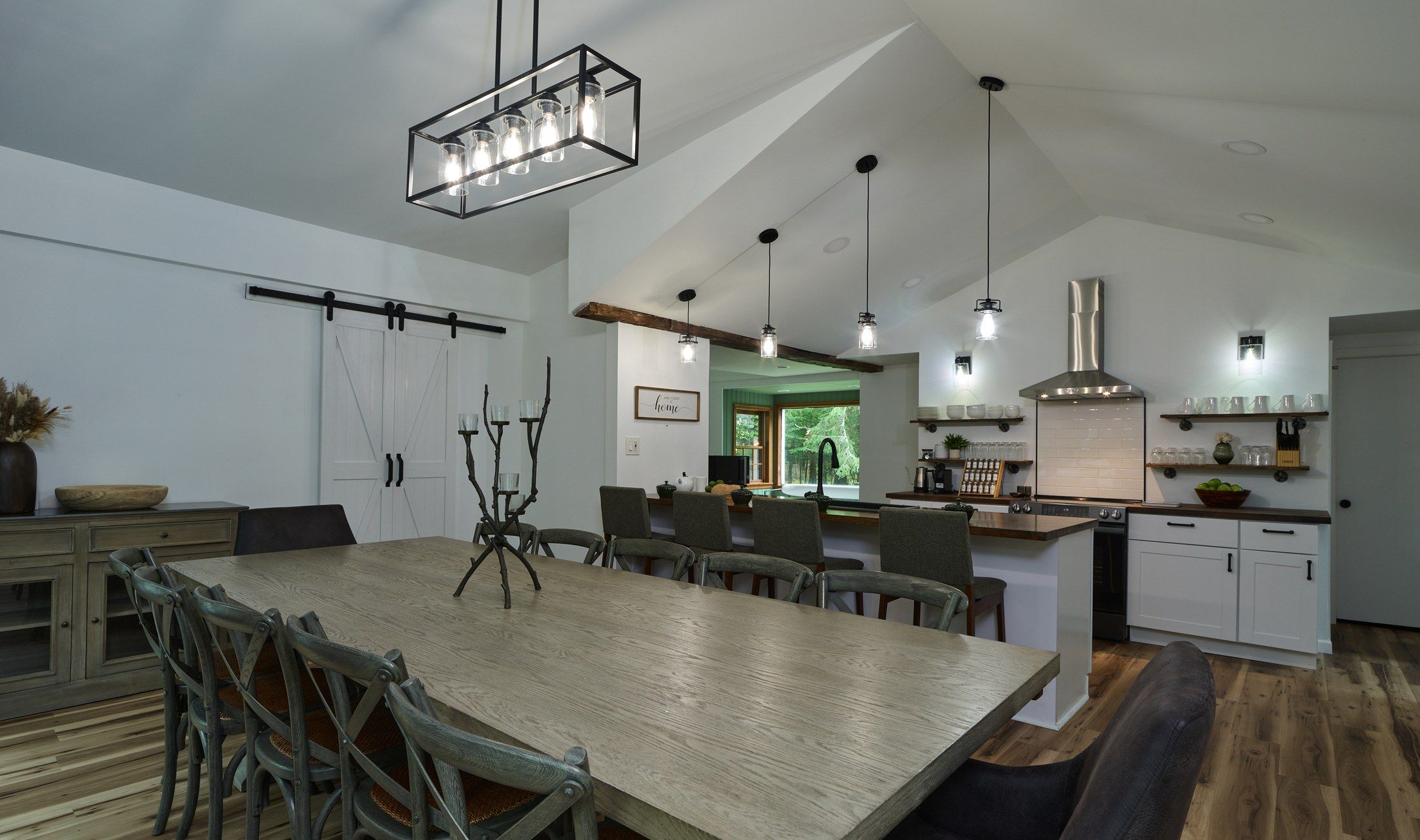 Une cuisine moderne dotée d’un îlot central, de luminaires suspendus et d’un coin repas avec une grande table et des chaises.