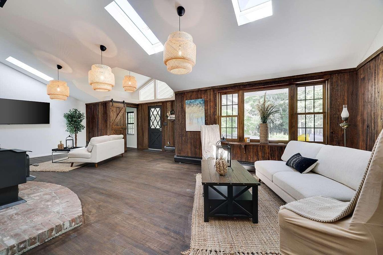 A spacious living room with a fireplace, a sofa, a coffee table, and a TV mounted on the wall.